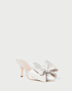 a white shoe with a large bow on the front and heel, in satin fabric