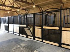 an indoor area with several stalls and horses in the stable, all made out of wood