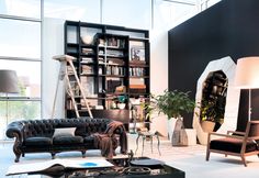 a living room filled with furniture and lots of windows next to a book shelf full of books