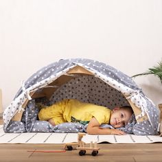 a little boy laying in a tent on the floor