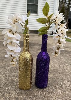 two vases with flowers in them sitting on the ground next to each other,