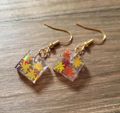 the earrings are made out of glass and have colorful fall leaves on each earring