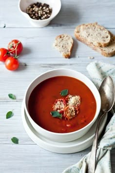 a bowl of tomato soup with bread on the side