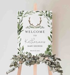 a welcome sign with greenery and antlers is displayed on an easel for the baby shower