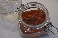 a glass jar filled with food sitting on top of a white table next to a metal spoon