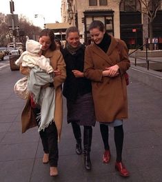 three women are walking down the street with one woman looking at her cell phone and smiling