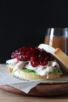 a sandwich with turkey, lettuce and cranberry sauce sitting on a cutting board