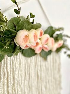 flowers are hanging from the side of a macrame wall decoration with green leaves and pink roses