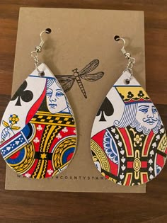 the earrings are designed to look like playing cards with dragonflys on them, sitting on a piece of cardboard