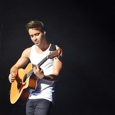 a young man playing an acoustic guitar on stage