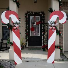 two large candy canes decorated with christmas decorations on the front steps of a house