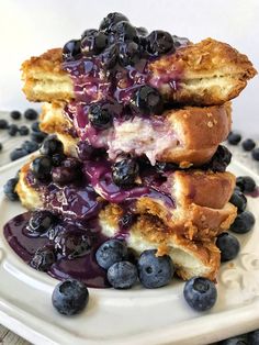 a stack of blueberry cheesecakes on a white plate with fresh blueberries