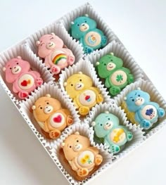 there are many different colored teddy bears in the cupcakes box on the table