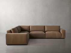 a brown leather sectional sofa sitting on top of a floor next to a white wall