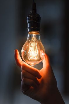 a light bulb that has been turned on by someone holding it in the air with their hand