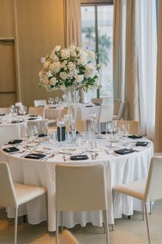 a table set up with white flowers and place settings