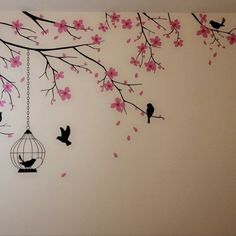 the wall is decorated with pink flowers and birdcage hanging from it's branches