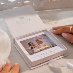 two women are sitting at a table with their wedding rings on top of the box