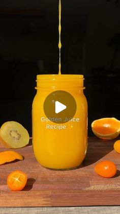 a jar filled with oranges sitting on top of a wooden table next to sliced oranges