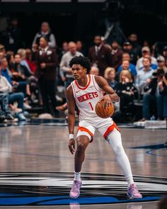 a man holding a basketball on top of a court