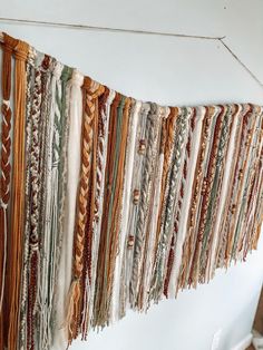 an assortment of different colored yarns hanging from a line on a wall in a room