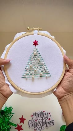 a person holding up a christmas tree embroidery kit