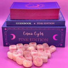 pink dices are stacked on top of each other in front of a purple book