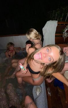 three women in a hot tub at night with one woman holding a toothbrush and the other looking up