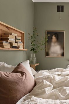 a bed with white sheets and pillows in a bedroom next to a book shelf filled with books