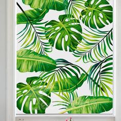 a window with green leaves on it and the blinds are closed to let in light