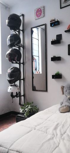 a bed with a stuffed animal sitting on top of it next to a wall mounted helmet rack