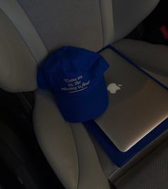 an apple laptop computer sitting on top of a blue hat