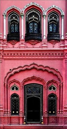 an ornate pink building with black doors and windows