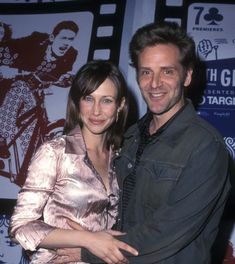 a man and woman standing next to each other in front of a wall with pictures on it