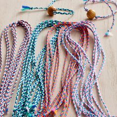 multicolored necklaces laid out on a wooden surface with beads attached to them