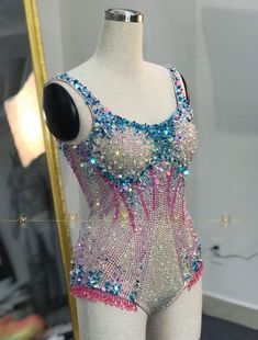 a mannequin wearing a colorful bodysuit with sequins and beads on it