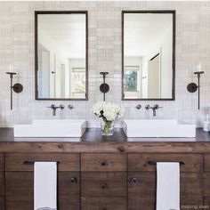 a bathroom with two sinks and mirrors on the wall