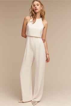 a woman in white jumpsuits and sandals standing up with her hands on her hips