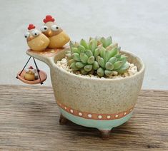 a potted plant sitting on top of a wooden table next to two little birds