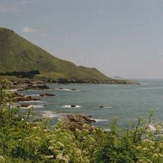 the water is calm and blue with green hills in the background