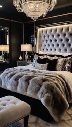 a luxurious bedroom with black walls, white bedding and a chandelier hanging from the ceiling