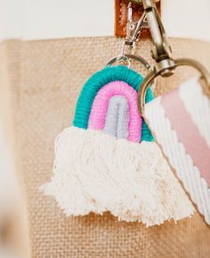 a keychain with a rainbow on it hanging from a bag handle that is made out of burlap