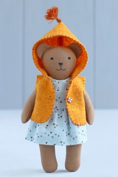 a teddy bear wearing a yellow jacket and dress with a hood on it's head