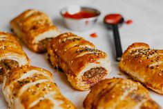 several sausage rolls on a white plate with dipping sauce