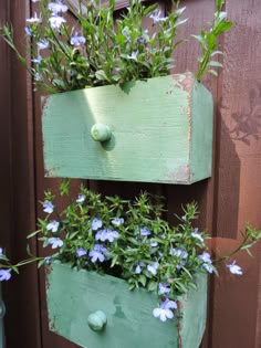 an old wooden box with flowers in it is hanging on the side of a fence