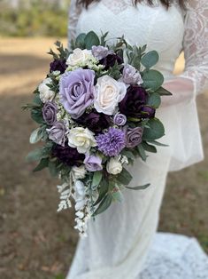 a bride holding a purple and white bouquet