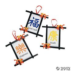 two framed pictures with chinese characters hanging from strings and ribbons on the front of them