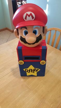 a nintendo mario birthday cake sitting on top of a wooden table in front of a dining room table