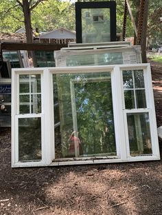 an open window sitting on the ground in front of trees