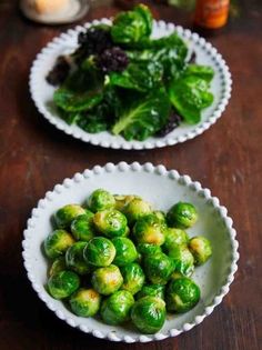 two white bowls filled with brussel sprouts on top of a wooden table